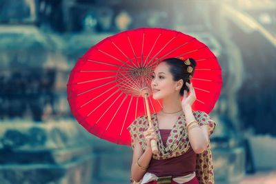 Young woman in traditional clothing holding paper umbrella