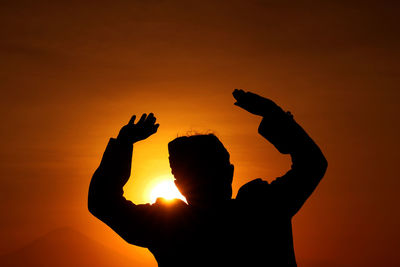 Low angle view of silhouetted man against sky during sunset