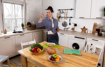 Young and beautiful housewife woman cooking in a white kitchen