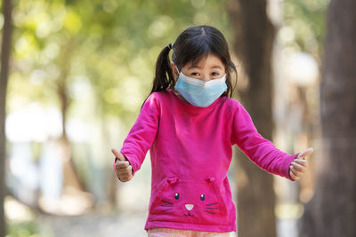 Portrait of girl wearing mask standing at park