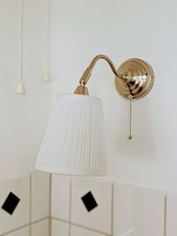 Close-up of electric lamp hanging on wall at home