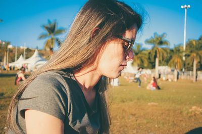 Side view of young woman wearing sunglasses against sky