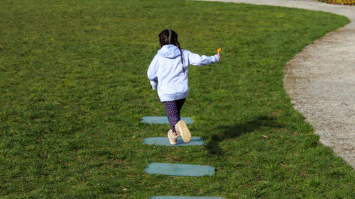 Full length of young woman exercising on grassy field