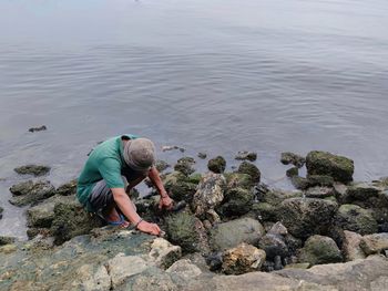 High angle view of man on rock in sea