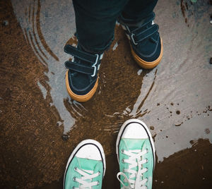 Low section of a person and a child standing by water