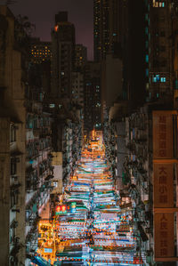 Illuminated market amidst buildings in city at night