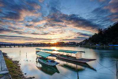 Sailboats moored in lake against sky during sunset