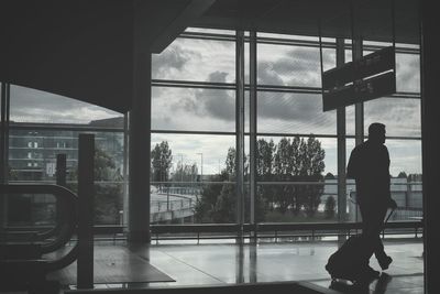 Silhouette of man with luggage walking in airport building