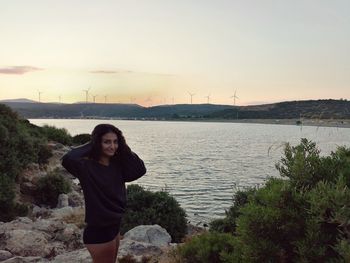 Portrait of young woman standing against sky