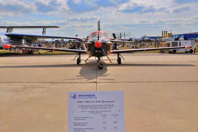 Airplane on airport runway against sky in city