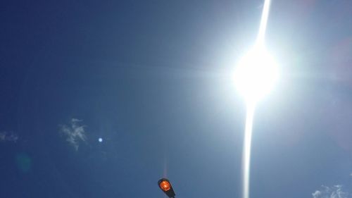 Low angle view of sun against blue sky