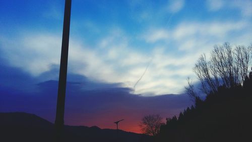 Low angle view of silhouette trees against blue sky