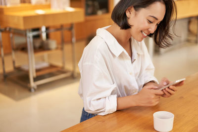 Young woman using mobile phone in cafe