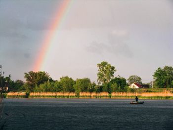 Scenic view of rainbow over lake against sky