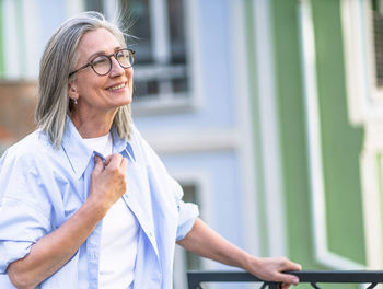 Concept of happiness with senior woman smiling with closed eyes in old city. 