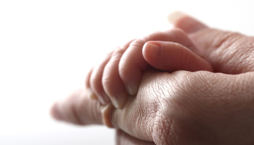 Close-up of baby hand against white background
