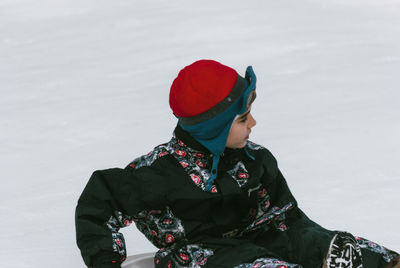 Boy tobogganing on snow covered field during winter