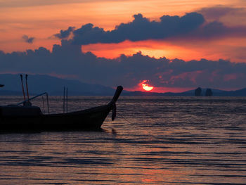 Silhouette boat in sea against orange sky
