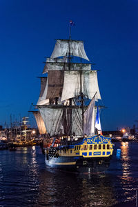 Sailboat sailing in sea against clear blue sky at dusk