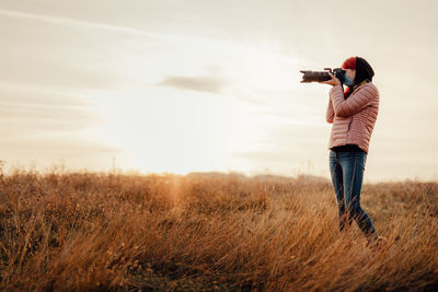 Full length of woman photographing on field