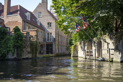 Canal amidst trees and buildings in city