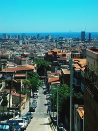 High angle view of street amidst buildings against clear blue sky