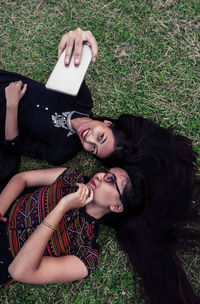 High angle view of young woman using mobile phone in grass