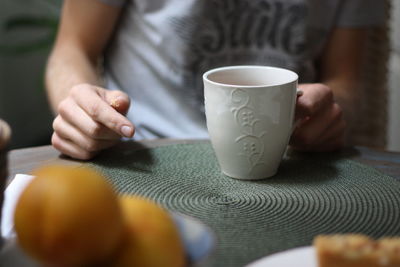 Close-up of woman holding coffee cup on table