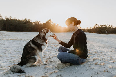 Side view of dog and woman sitting outdoors