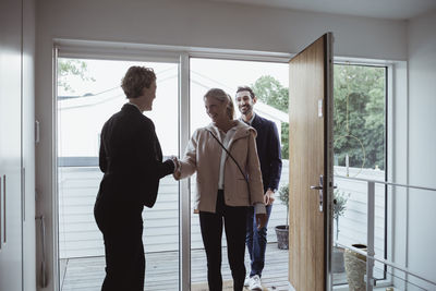 Smiling real estate agent greeting couple in new house