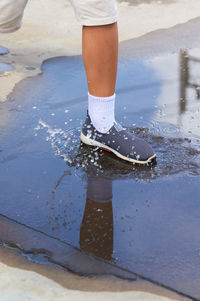 Low section of woman standing on wet puddle