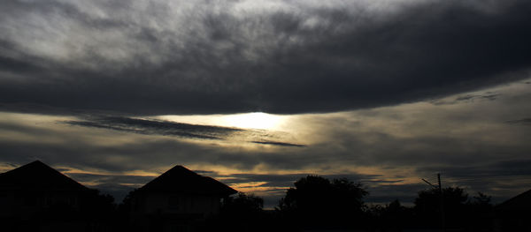 Silhouette houses against sky during sunset