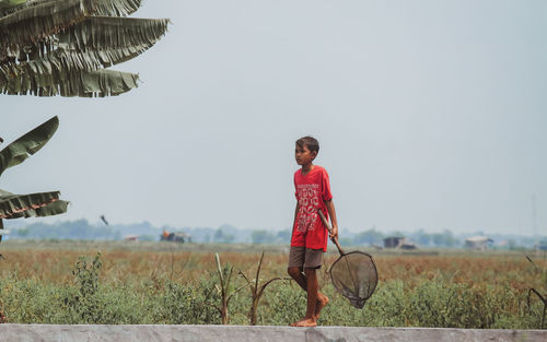 Rear view of woman standing on field against clear sky