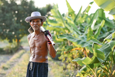 Portrait of shirtless man standing against plants