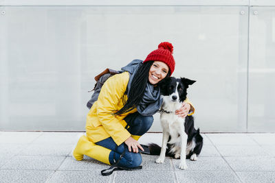 Full length of woman with dog sitting in snow