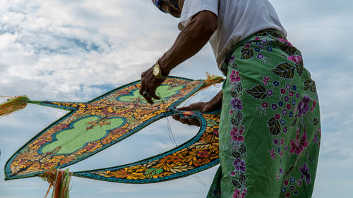 Midsection of man holding kite against sky