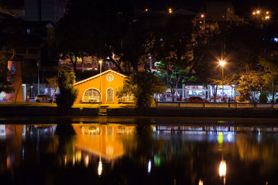 Illuminated building by river at night