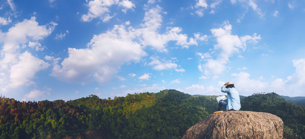 Rear view of man standing on mountain against sky