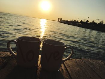 Close-up of coffee cup on table against sky during sunset