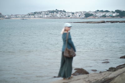 Rear view of woman standing by sea against sky