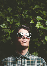 Young man wearing sunglasses against plants