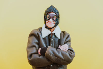 Portrait of senior woman wearing glasses while standing against yellow background
