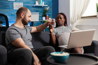 Young woman using mobile phone while sitting at home