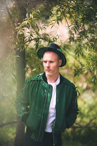 Portrait of young man standing against trees