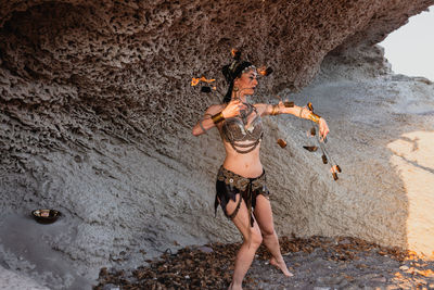 Full length of woman standing on rock by sea