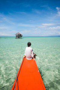 Rear view of woman sitting on boat in sea