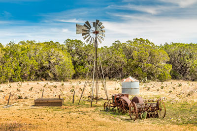 Texas hill country spring landscape with a windmill and a hey tedder