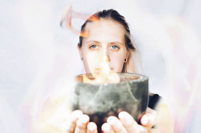 Digital composite image of woman holding fire in bowl