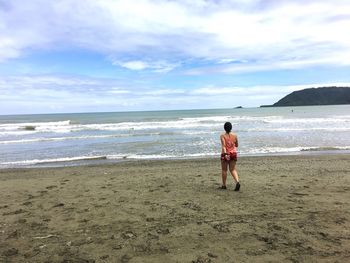 Rear view of man on beach against sky