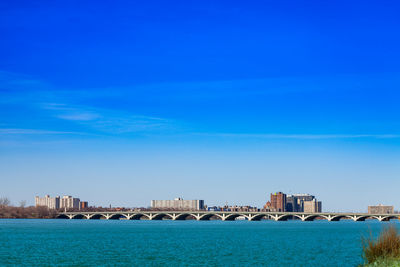 Sea by buildings against blue sky